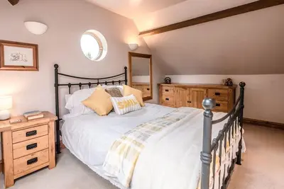 a bedroom with a large bed and a wooden dresser at The Old Coach House, Leiston in Leiston