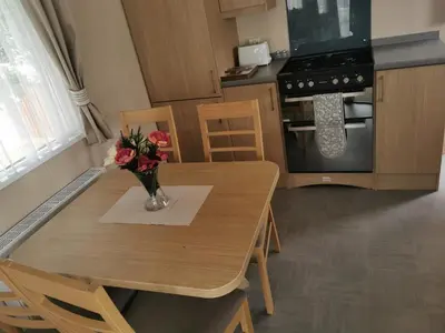 a kitchen with a table with a vase of flowers on it at Happy Place in West Mersea