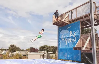 a person jumping off a life bee playground at Brand New Modern Holiday Home - Haven The Orchards Holiday Park in Saint Osyth