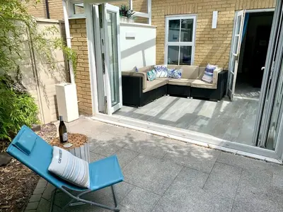 a patio with a blue chair and a couch at Vibrant Mill Road Oasis - Peaceful House with Garden near station in Cambridge