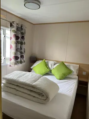 a bedroom with a bed with green pillows at Lovely place in Saint Osyth