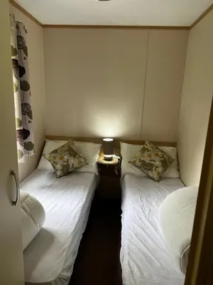 two twin beds in a small room with a table at Lovely place in Saint Osyth