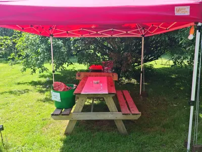 a picnic table under a red tent with a bucket at The Potting Shed in Manuden