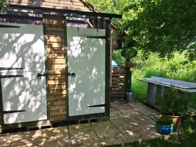 a greenhouse with two glass doors in a yard at The Potting Shed in Manuden