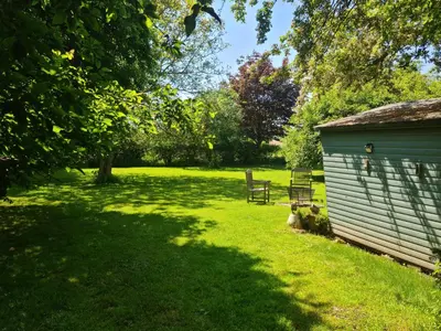 a bench sitting next to a shed in a field at The Potting Shed in Manuden
