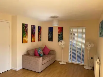 a living room with a couch and some paintings on the wall at Homely & Warm Trumpington House w Parking, 5 mins drive to Bio Medical Campus, Addenbrooke's & Papworth hospitals in Cambridge