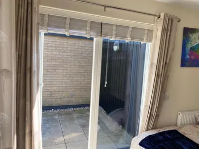 a bedroom with a sliding glass door to a window at Homely & Warm Trumpington House w Parking, 5 mins drive to Bio Medical Campus, Addenbrooke's & Papworth hospitals in Cambridge
