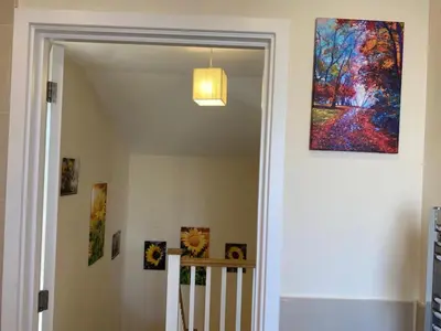 a hallway with a painting on the wall and a staircase at Homely & Warm Trumpington House w Parking, 5 mins drive to Bio Medical Campus, Addenbrooke's & Papworth hospitals in Cambridge