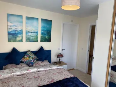 a bedroom with a bed and three paintings on the wall at Homely & Warm Trumpington House w Parking, 5 mins drive to Bio Medical Campus, Addenbrooke's & Papworth hospitals in Cambridge