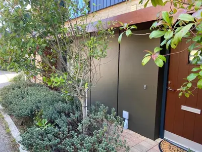 a garage with a tree next to a building at Homely & Warm Trumpington House w Parking, 5 mins drive to Bio Medical Campus, Addenbrooke's & Papworth hospitals in Cambridge