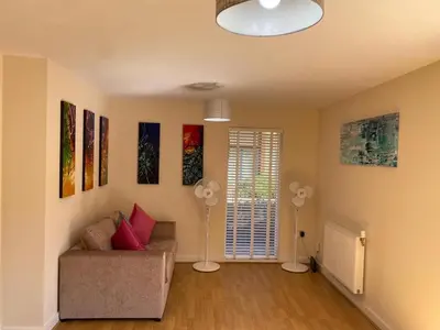 a living room with a couch and paintings on the wall at Homely & Warm Trumpington House w Parking, 5 mins drive to Bio Medical Campus, Addenbrooke's & Papworth hospitals in Cambridge