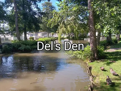 a river with a sign that reads delis den at Del's den lakeside weeley bridge in Weeley