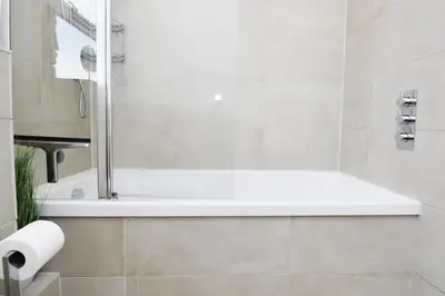 a white bathroom with a tub and a toilet paper roll at Modern and Cosy Flat For 4 in Cherry Hinton