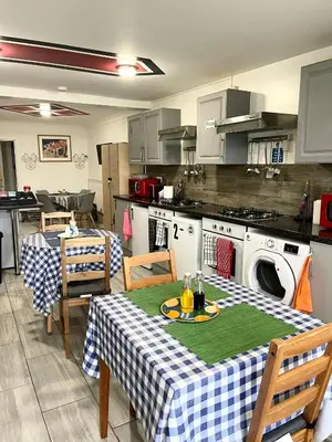a kitchen with two tables and a kitchen with a washing machine at Penn Gardens Flat 1 - 2 - 3 & 4 Apartments in Havering atte Bower