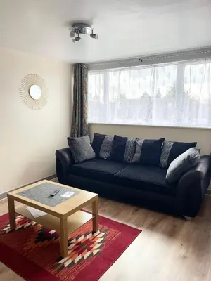 a living room with a black couch and a table at Penn Gardens Flat 1 - 2 - 3 & 4 Apartments in Havering atte Bower