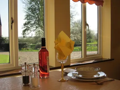 a bottle of wine sitting on a table next to a window at Colston Hall Cottages in Framlingham