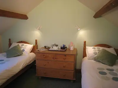 a bedroom with two beds and a wooden dresser at Colston Hall Cottages in Framlingham