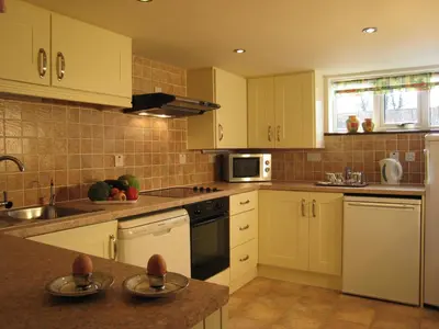 a kitchen with white cabinets and white appliances at Colston Hall Cottages in Framlingham