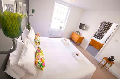 a bedroom with a white bed with a tie on it at Dog and Whistle Pub in Hertford