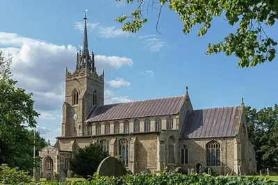 an old church with a tower and a clock on it at The Lodge - 2 acres of garden with hot tub and fire pit and BBQ in East Harling