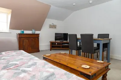 a bedroom with a table and chairs and a television at The Thatched Flat at The Sorrel Horse in Shottisham