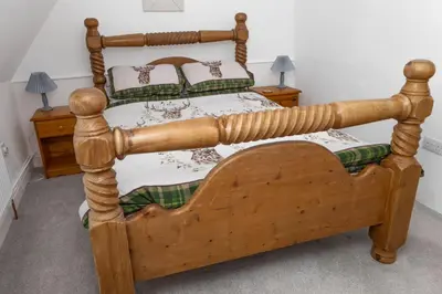 a wooden bed in a room with two night stands at The Thatched Flat at The Sorrel Horse in Shottisham