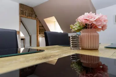 a table with a vase with pink flowers on it at The Thatched Flat at The Sorrel Horse in Shottisham