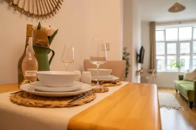 a table with two wine glasses and plates on it at Boho Style - KING BED, Central, Super FAST Wi-Fi in Cambridge