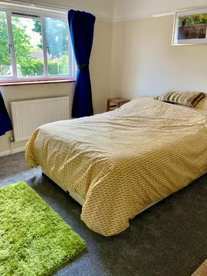 a bedroom with a bed and a green rug at Comfortable rooms upstairs at number 8 in Moulton