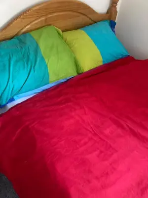 a bed with multicolored sheets and pillows at Comfortable rooms upstairs at number 8 in Moulton