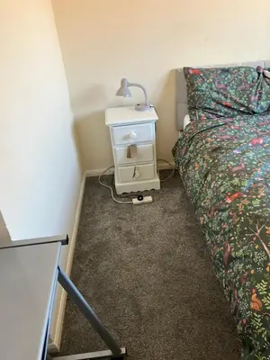 a bedroom with a bed and a night stand with a lamp at Comfortable rooms upstairs at number 8 in Moulton