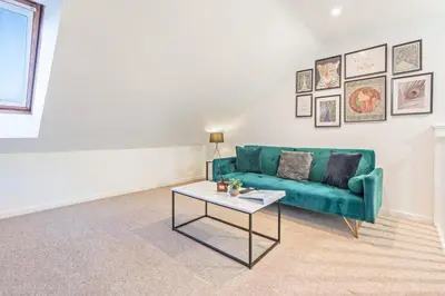 a living room with a green couch and a table at Comfortable 4-BDR House, Sleeps 7, WIFI, Secure Parking in Cambridge