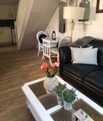a living room with a black couch and a table at Dinky cottage in Brightlingsea