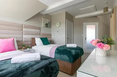 a bedroom with two beds and a clock on the wall at Weekly & Monthly Rates! Stunning Home By Stansted Airport in Bishops Stortford