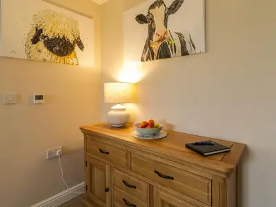 a room with a wooden dresser with a bowl of fruit on it at Bramley Cottage in Clacton-on-Sea