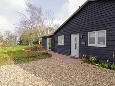 a black house with a white door and a yard at Bramley Cottage in Clacton-on-Sea