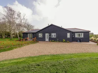 a black house with a gravel driveway at Bramley Cottage in Clacton-on-Sea