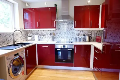 a kitchen with red cabinets and a washing machine at Stunning Apartment close to Cambridge Station with FREE Parking! in Cambridge