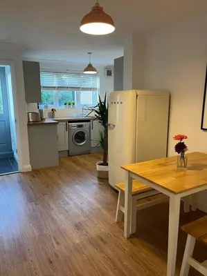 a kitchen with a table and a refrigerator in a room at Chic 2 bedroom cottage in Willingham