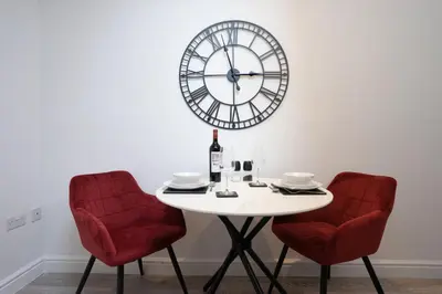 a table with two chairs and a clock on the wall at The Den - KING BED, 5 min walk to City Centre in Cambridge