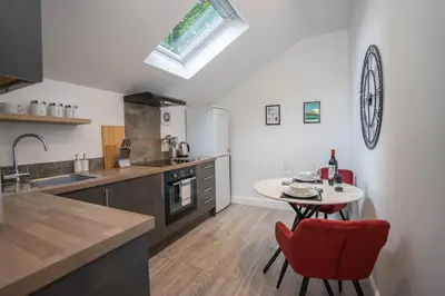 a kitchen with a red chair and a table at The Den - KING BED, 5 min walk to City Centre in Cambridge