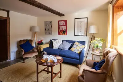 a living room with a blue couch and chairs at Church Cottage in Halesworth