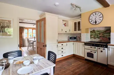 a kitchen with a table and a clock on the wall at Church Cottage in Halesworth