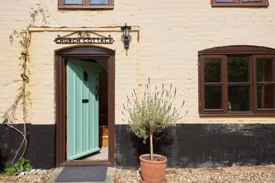 a building with a green door and a window at Church Cottage in Halesworth