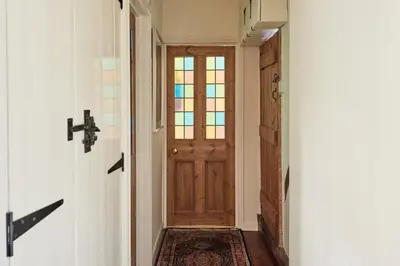 a hallway with a wooden door and a rug at Church Cottage in Halesworth