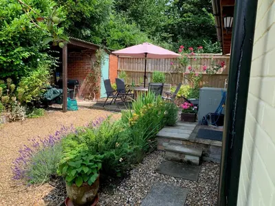a garden with a table and chairs and an umbrella at Church Cottage in Halesworth