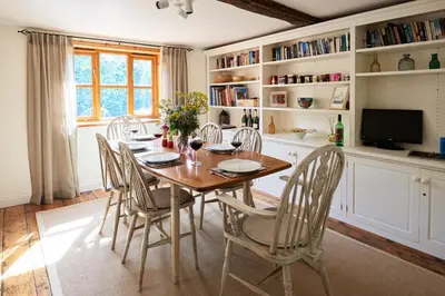 a dining room with a wooden table and chairs at Church Cottage in Halesworth