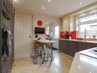a kitchen with a table and stools in it at 256 London Road in Colchester