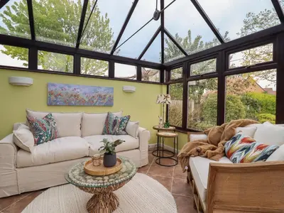 a conservatory with two couches and a table at 256 London Road in Colchester