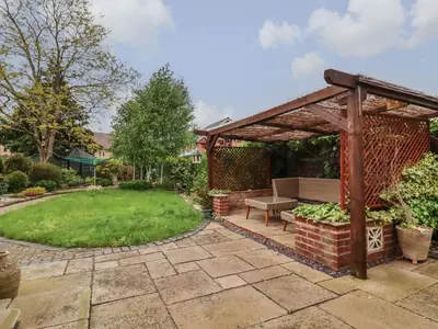 a wooden pergola with a bench in a garden at 256 London Road in Colchester